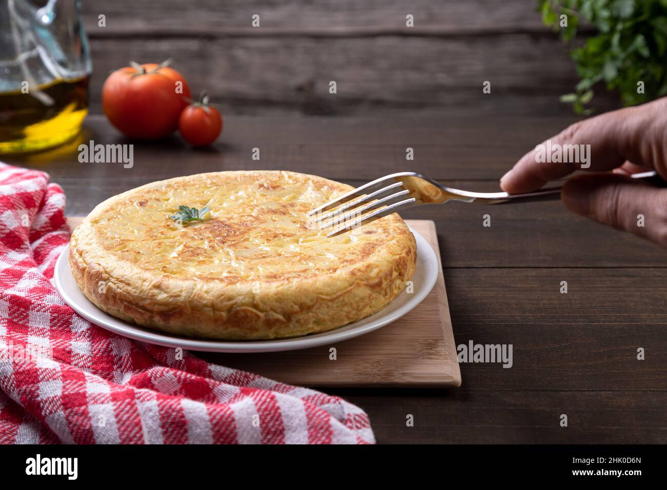 Spanisches Omelett mit Gabel auf rustikalem Hintergrund von Hand abholen. Traditionelle spanische Küche. Stockfoto