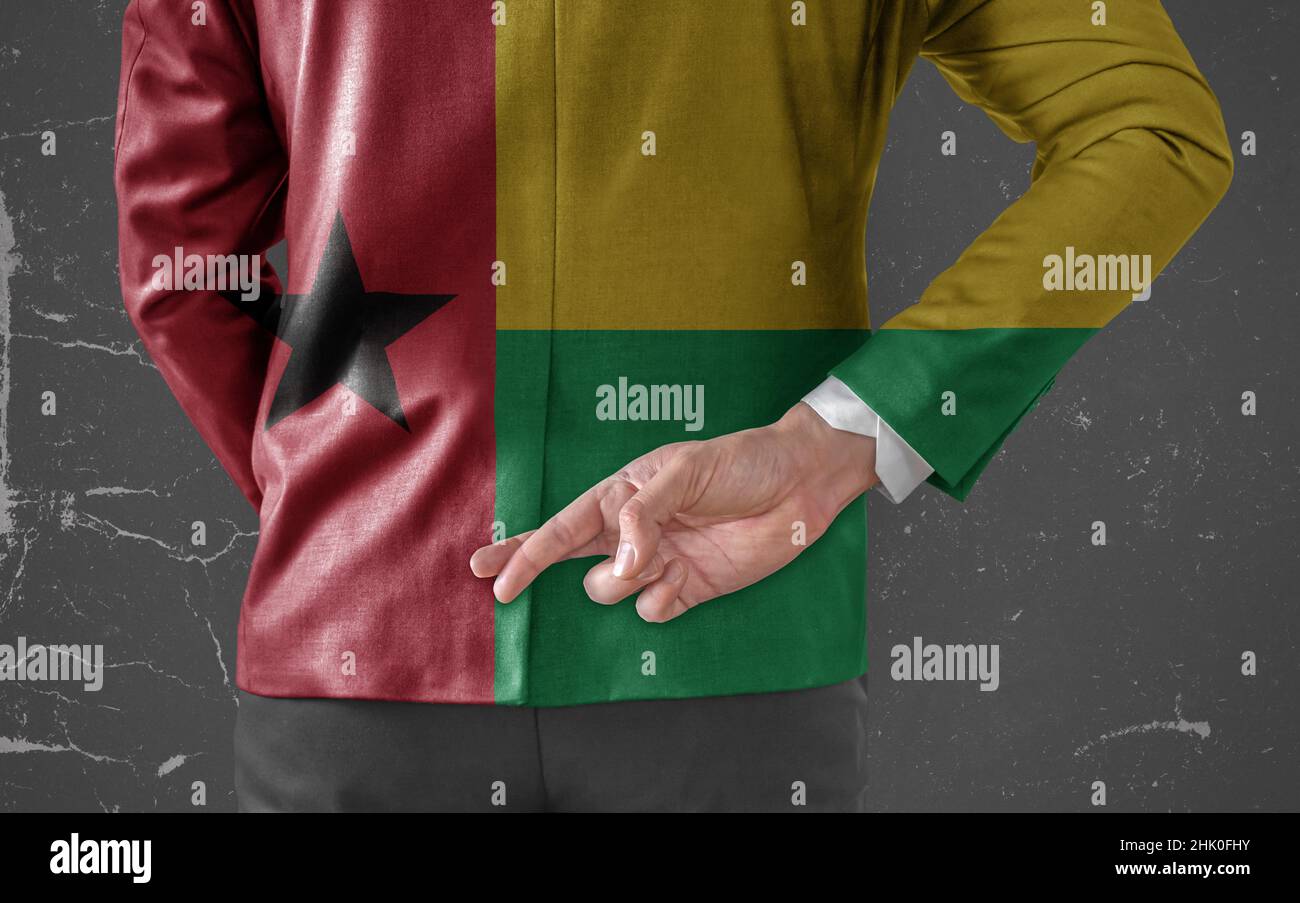 Businessman Jacke mit Flagge von Guinea Bissau mit gekreuzten Daumen hinter dem Rücken Stockfoto