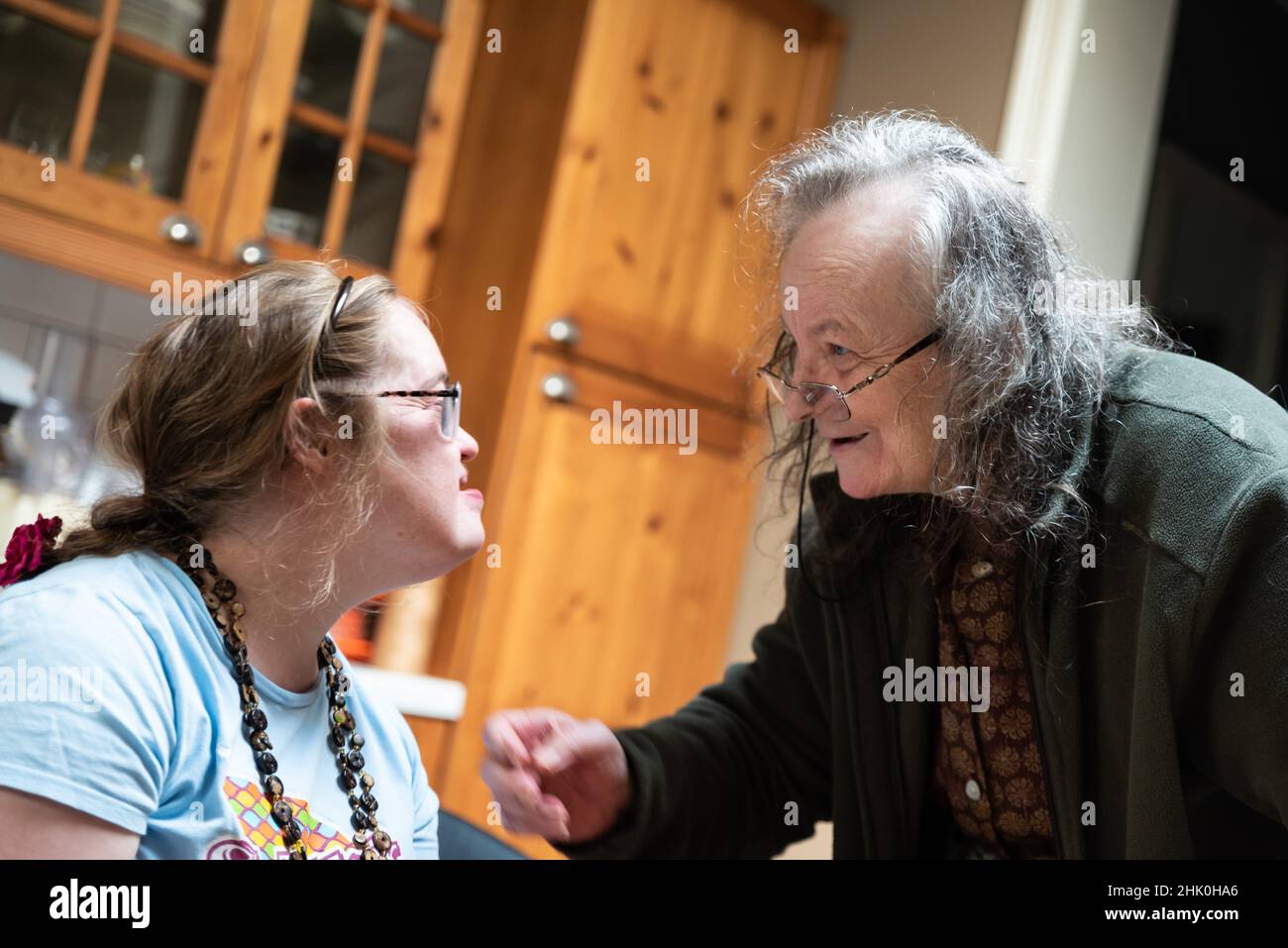 Hachendover, Flämisch-Brabant, Belgien - 09 20 2021: Behinderte 39-jährige Frau und ihre 83-jährige Mutter, die sich zu Hause in der Küche amüsieren. Stockfoto