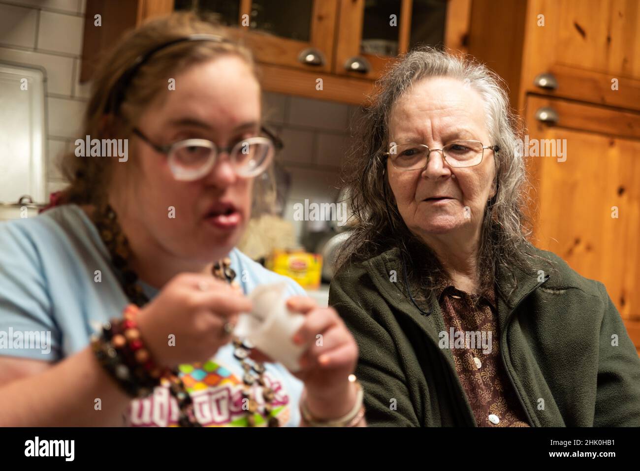Hachendover, Flämisch-Brabant, Belgien - 09 20 2021: Behinderte 39-jährige Frau und ihre 83-jährige Mutter, die sich zu Hause in der Küche amüsieren. Stockfoto