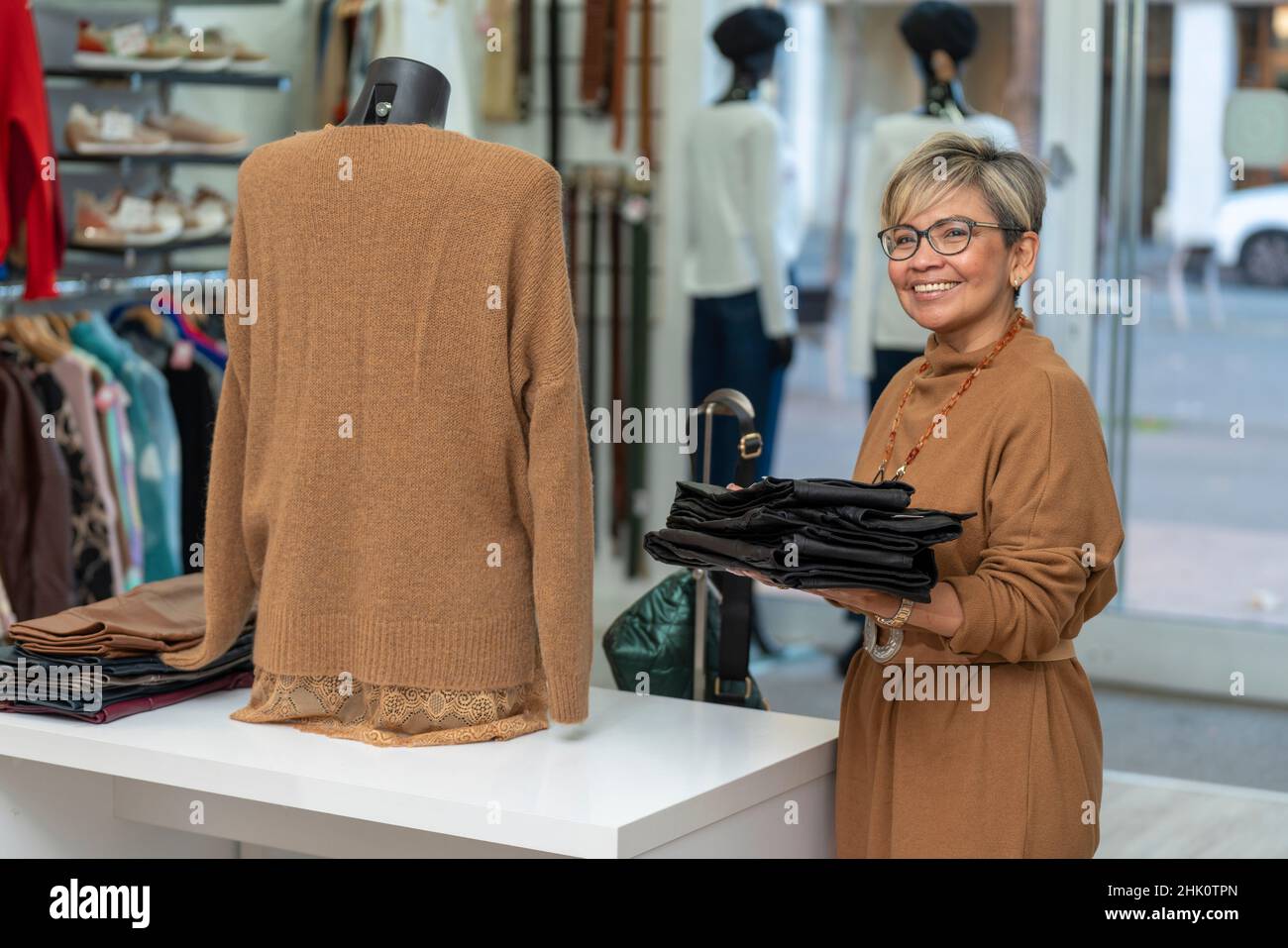 Senior latin Frau Kleidung Store Angestellter Blick auf Kamera Stockfoto
