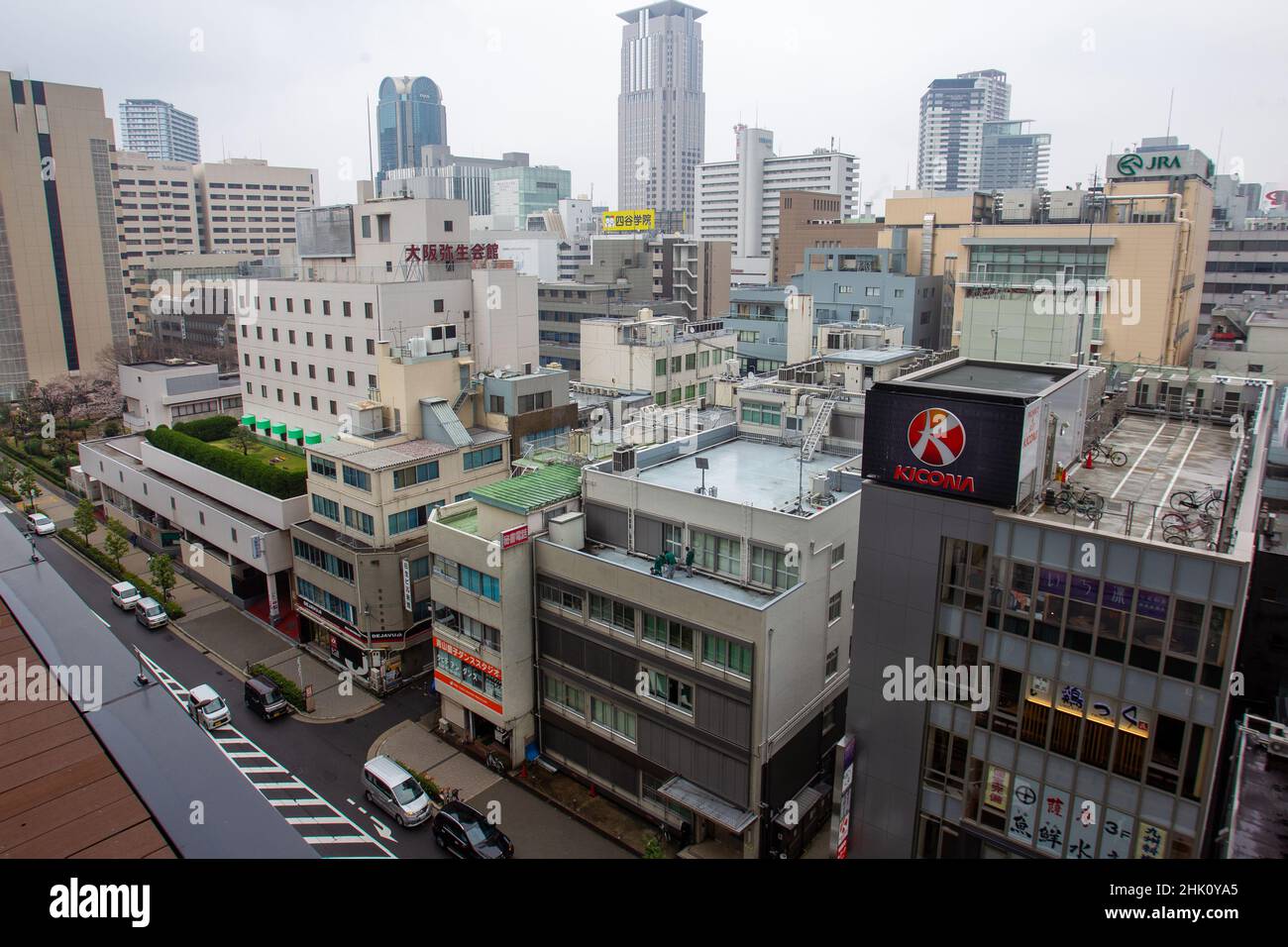 Stadtbild, Stadtpanorama von Osaka aus einem anderen hohen Gebäude. Auf einem Dach oder Balkon - grüner Garten - Gras und Sträucher oder Bäume. Auf einem Dach Parkplatz f Stockfoto