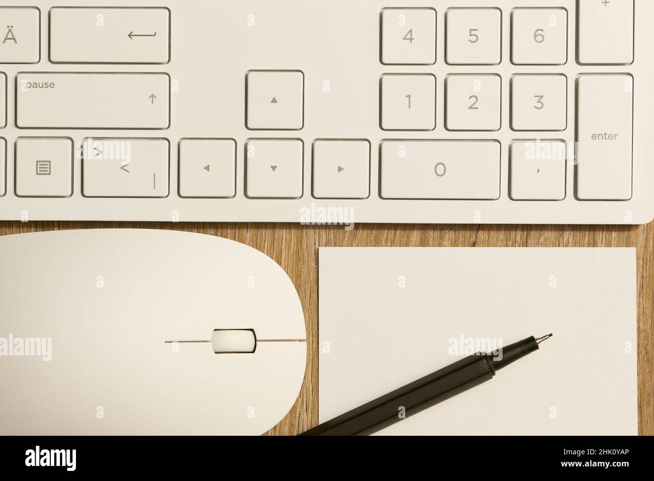 Tastatur von einem Computer und einer Computermaus sowie Stift und Papier auf einem Schreibtisch im Büro Stockfoto