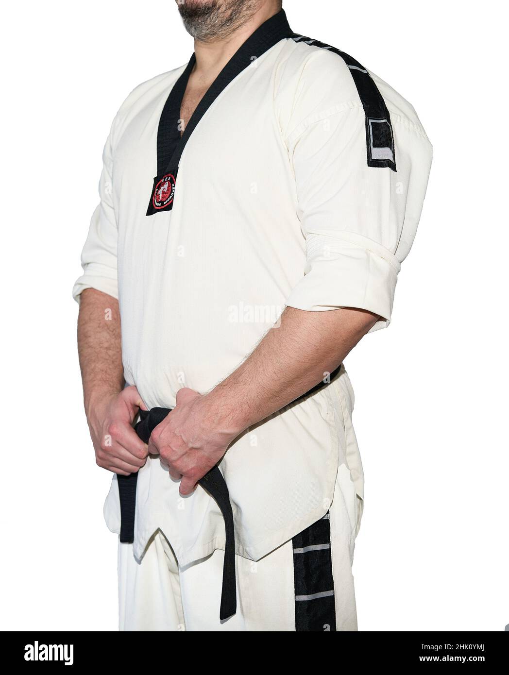 Mann in Taekwondo-Kampfkunstuniform, der seinen schwarzen Gürtel hält, wobei beide Hände auf dem weißen Hintergrund isoliert sind. Stockfoto