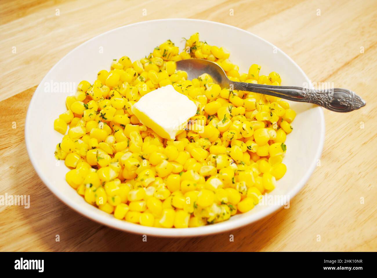 Frischer gelber Mais in einer weißen Schüssel mit einer Pat Butter serviert Stockfoto