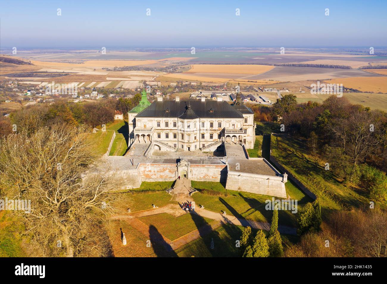 Luftaufnahme: Schloss Pidhirtsi, im Dorf Pidhirtsi im Gebiet Lviv, Ukraine, Sonnenuntergang über Herbstpark auf Hügeln mit bunten Bäumen. Stockfoto