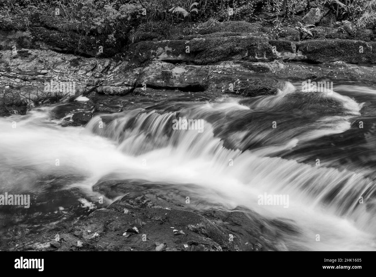 Lange Exposition eines Wasserfalls auf dem East Lyn Fluss Fließt durch den Wald bei Watersmeet im Exmoor Nationalpark Stockfoto