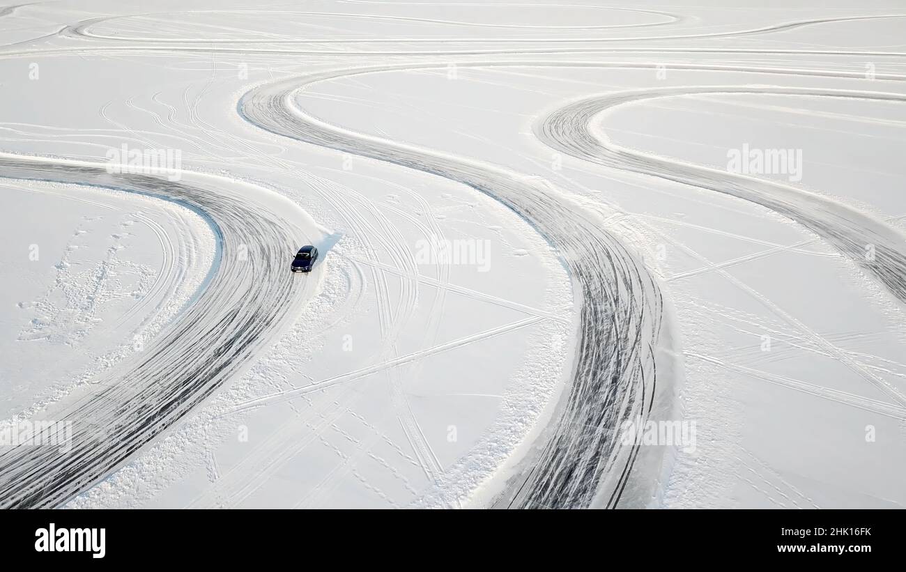 Ein Auto, das auf einer Landstraße durch den Winterwald fährt. Draufsicht von der Drohne. Luftaufnahme der schneebedeckten Straße im Winter, vorbeifahrende Autos. Draufsicht o Stockfoto