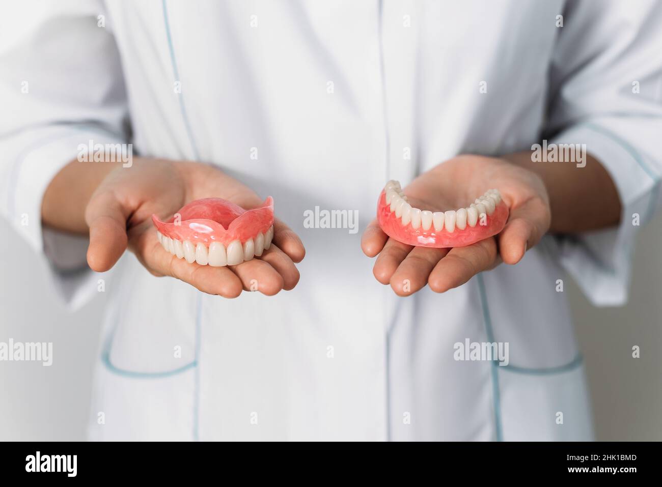 Der Zahnarzt hält Prothesen in den Händen. Zahnprothese in den Händen des Arztes Nahaufnahme. Vorderansicht der kompletten Prothese. Zahnmedizin Konzept Stockfoto