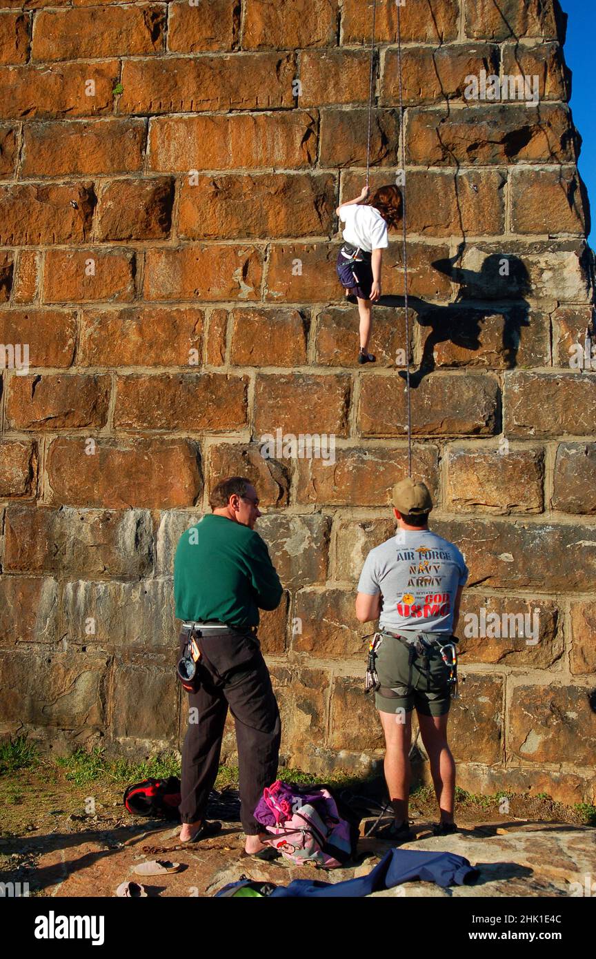 Ein junges Mädchen stößt eine Steinblockwand nieder Stockfoto
