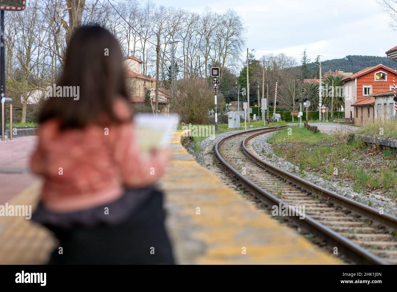 Ein Mädchen wartet am Bahnhof in einer Stadt auf die Bahnlesung Stockfoto