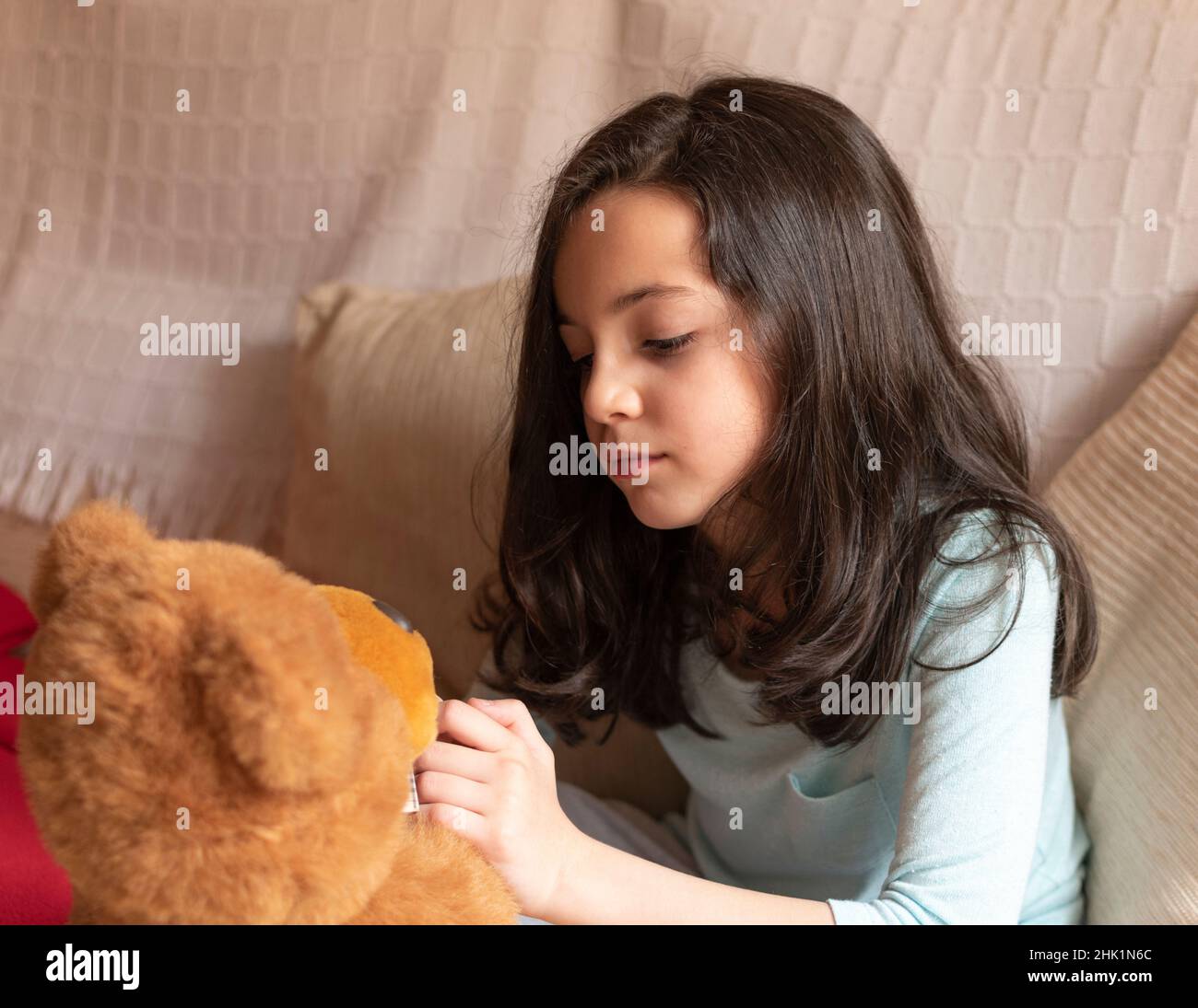 Mädchen, das in ihrem Haus mit ihrem braunen Teddybären spielt Stockfoto
