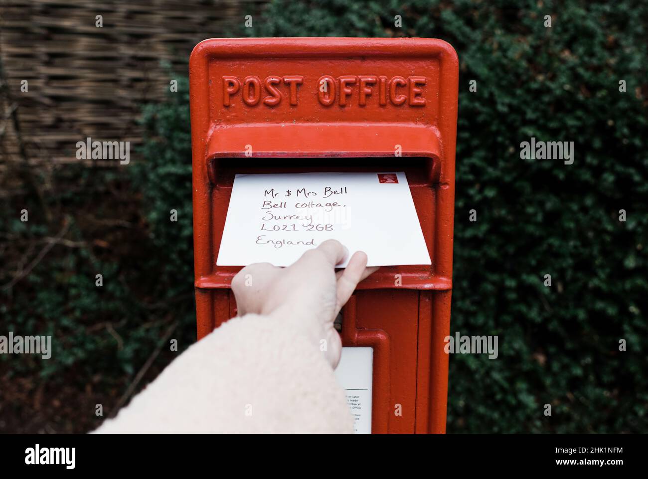 Handposting einen Brief an einem traditionellen englischen Briefkasten Stockfoto