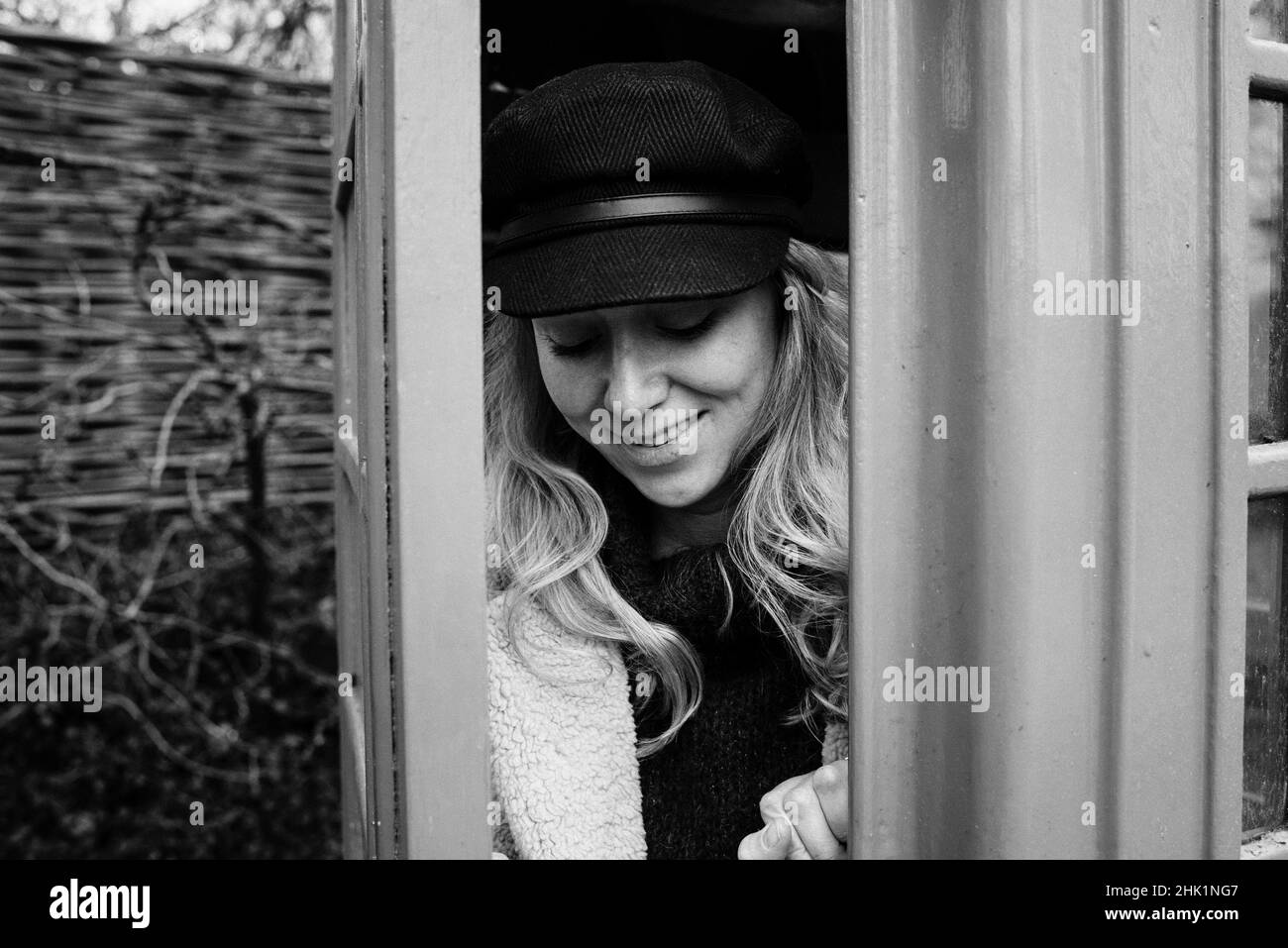 Schwarz-Weiß-Porträt einer Frau in einer englischen Telefonbox Stockfoto