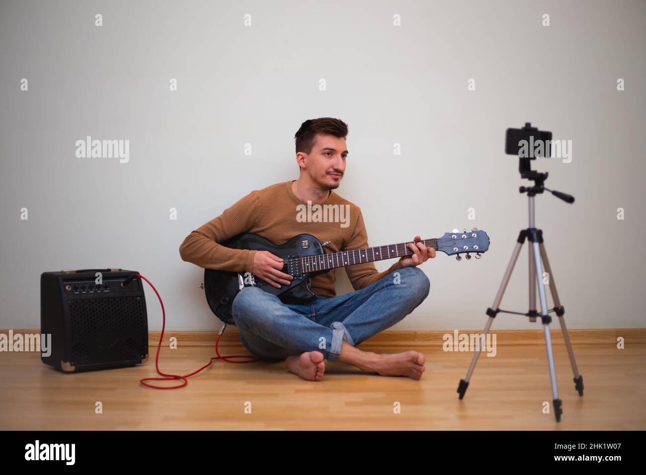 Junger Mann, der vor der Kamera auf einer Gitarre spielt Stockfoto