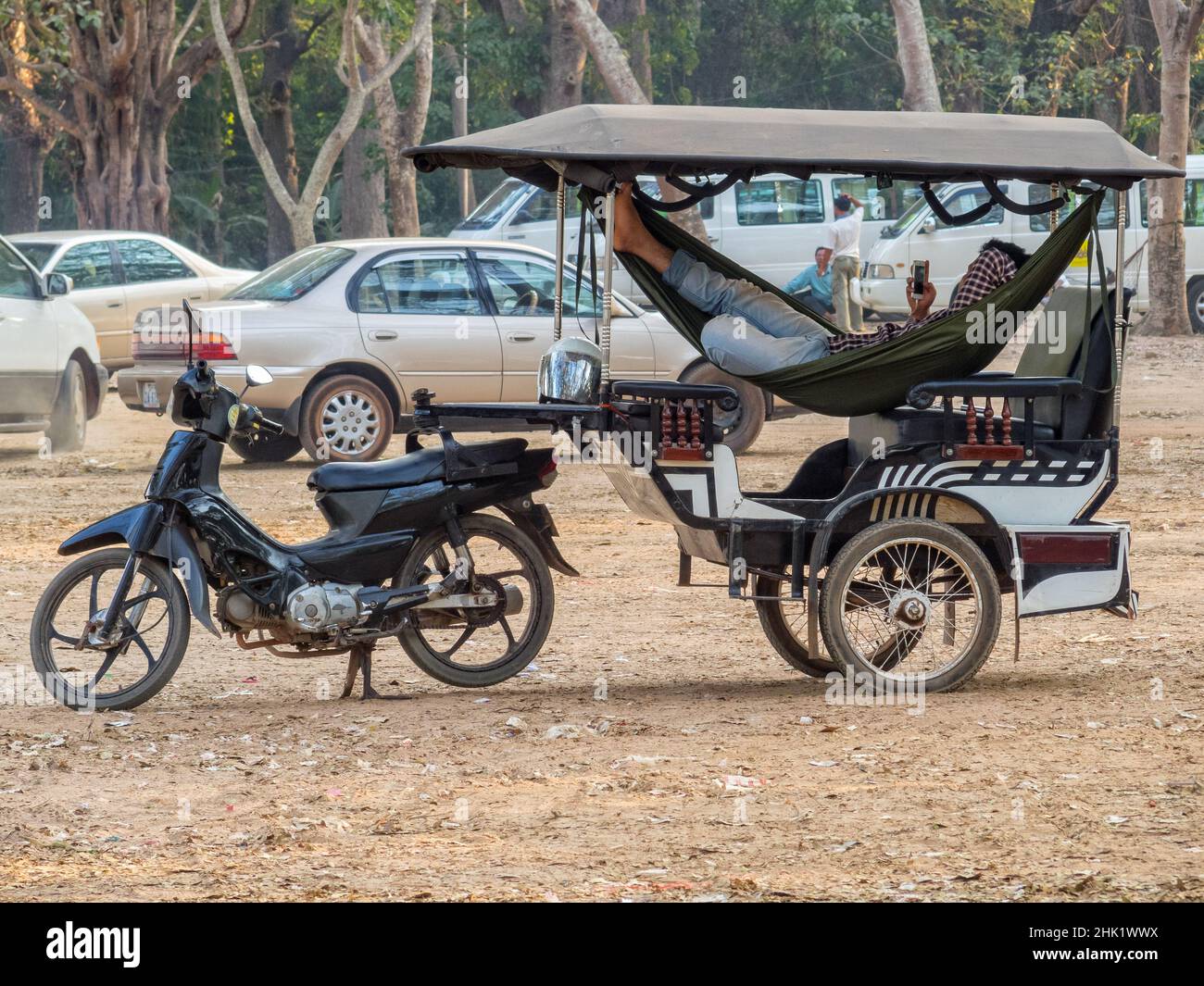 Entspannender Tuk-Tuk-Fahrer wartet auf seine Passagiere auf dem Parkplatz Angkor Wat - Siem Reap, Kambodscha Stockfoto