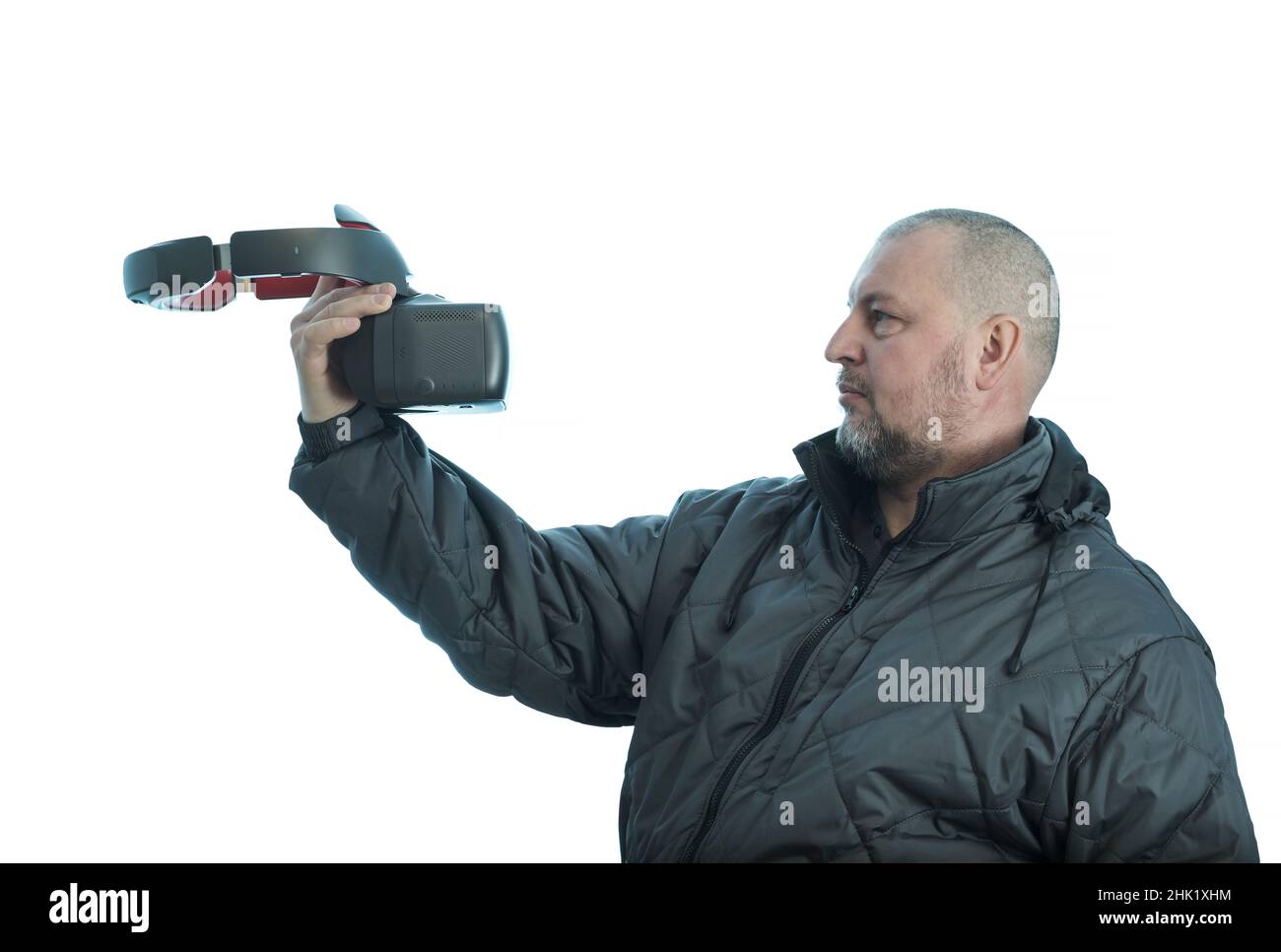 Ein Mann hält vor sich eine vr Brille in der Hand und schaut sie an. Stockfoto