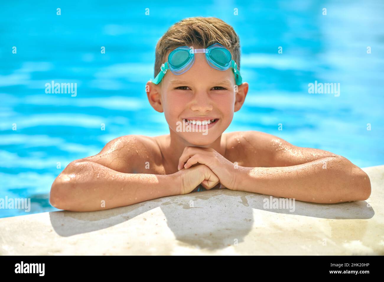 Junge guckt aus dem Pool und schaut auf die Kamera Stockfoto