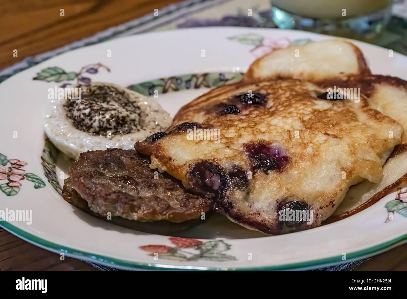 Frühstück mit Heidelbeer-Buttermilch-Pfannkuchen, Wurst und pochierten Eiern. Stockfoto