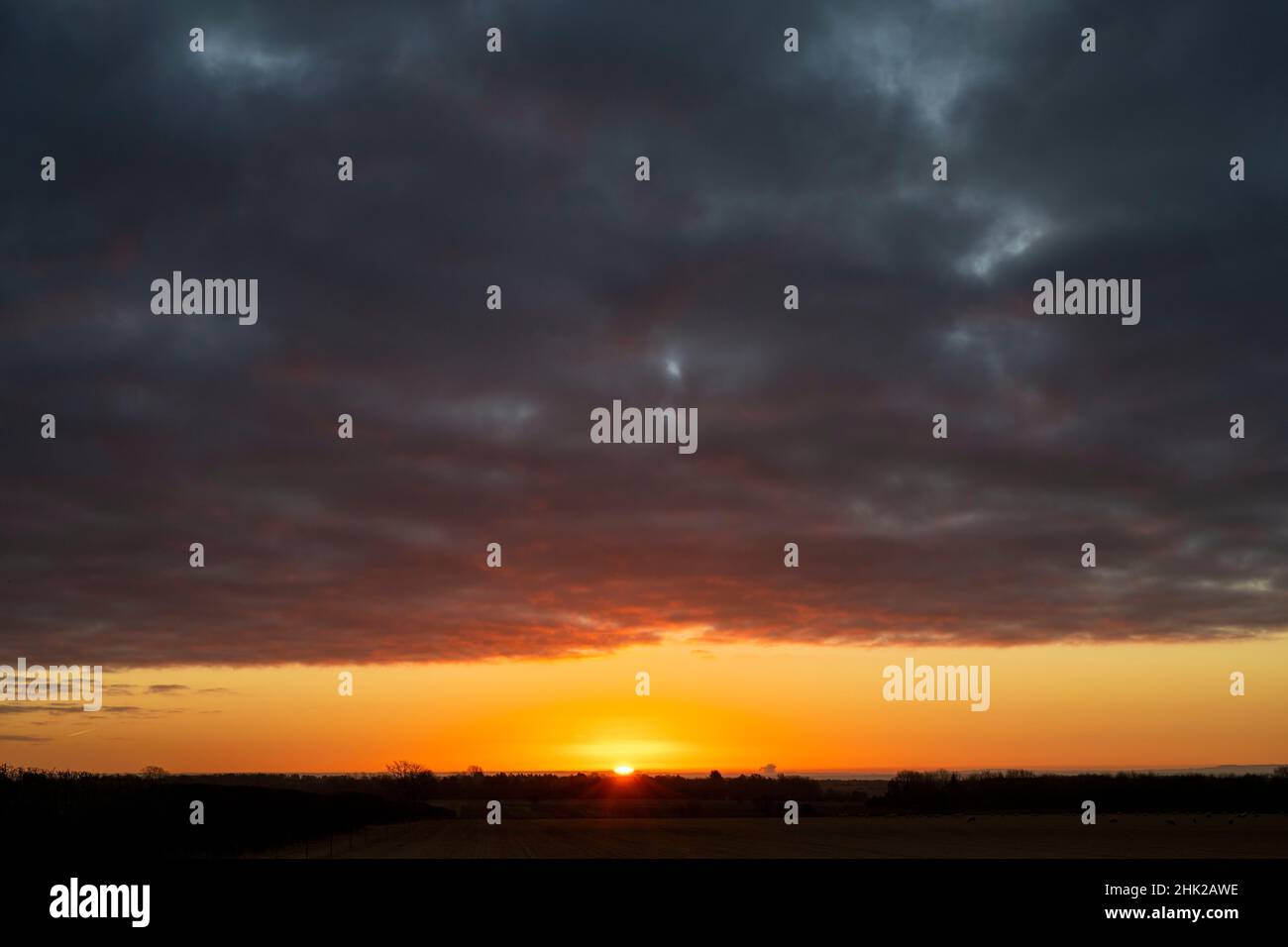 Dunkler wolkiger Himmel bei Sonnenaufgang in der Landschaft von cotswold. Cotswolds, Gloucestershire, England Stockfoto