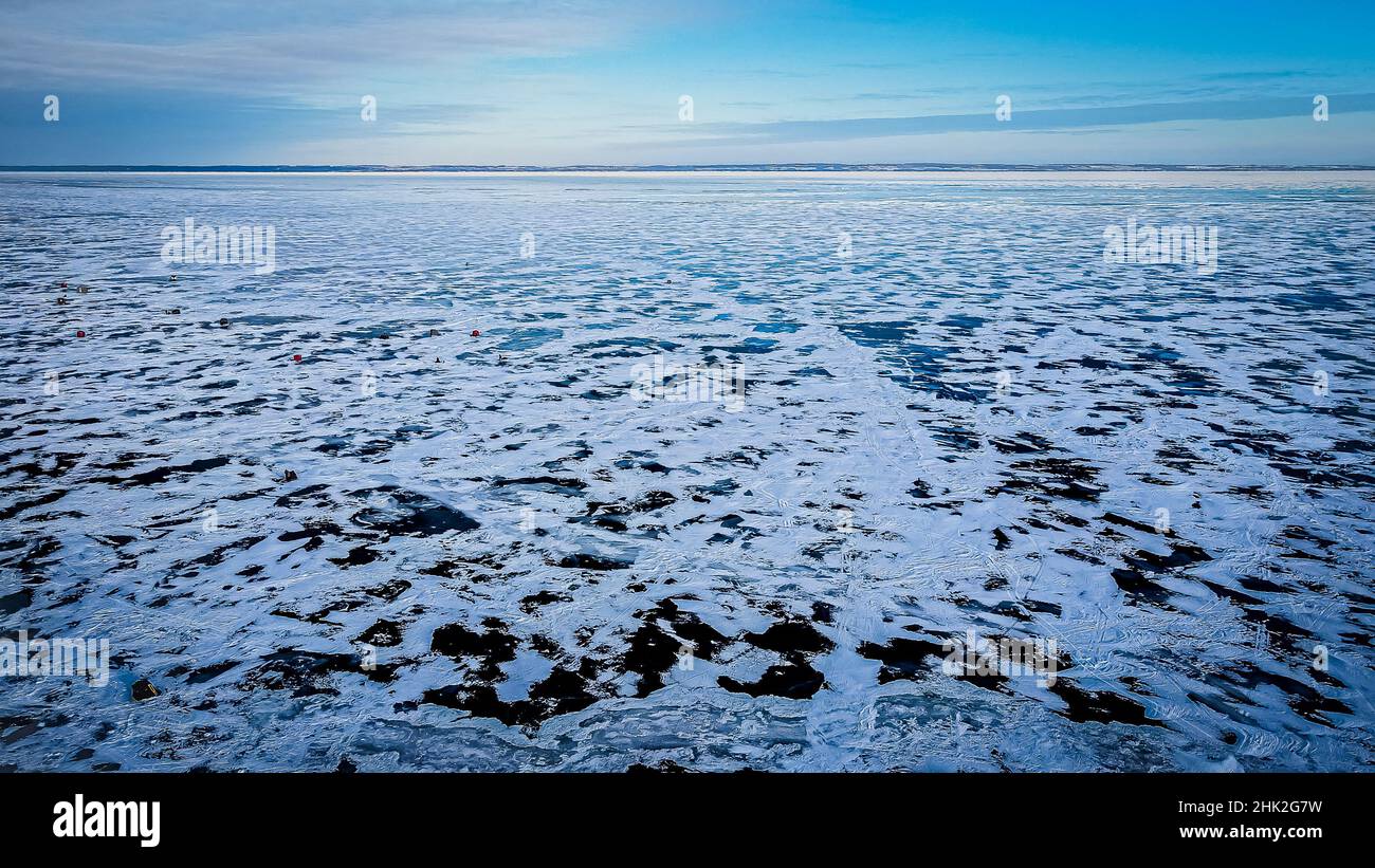 Schnee bedeckt teilweise die gefrorene Seenoberfläche. Schöner Himmel über dem Himmel mit einer gefrorenen Oberfläche. Die andere Seite des Sees ist zu sehen. Stockfoto