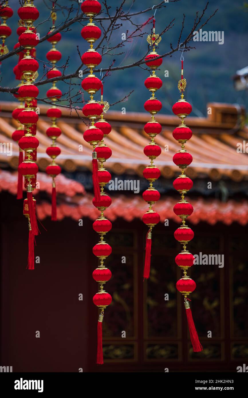 Rote Dekorationen hängen von Bäumen im chinesischen Tempelkomplex Stockfoto