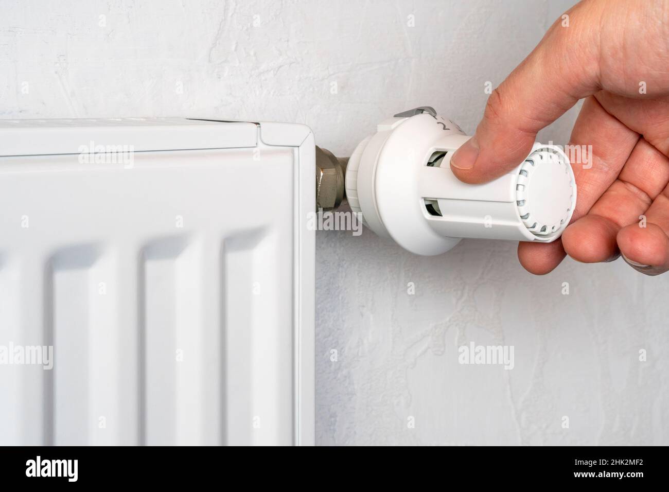 Mit der Hand dreht sich der Knopf für die Batterieheizung. Heizung in einer Wohnung, zu Hause. Heizpreise. Stockfoto