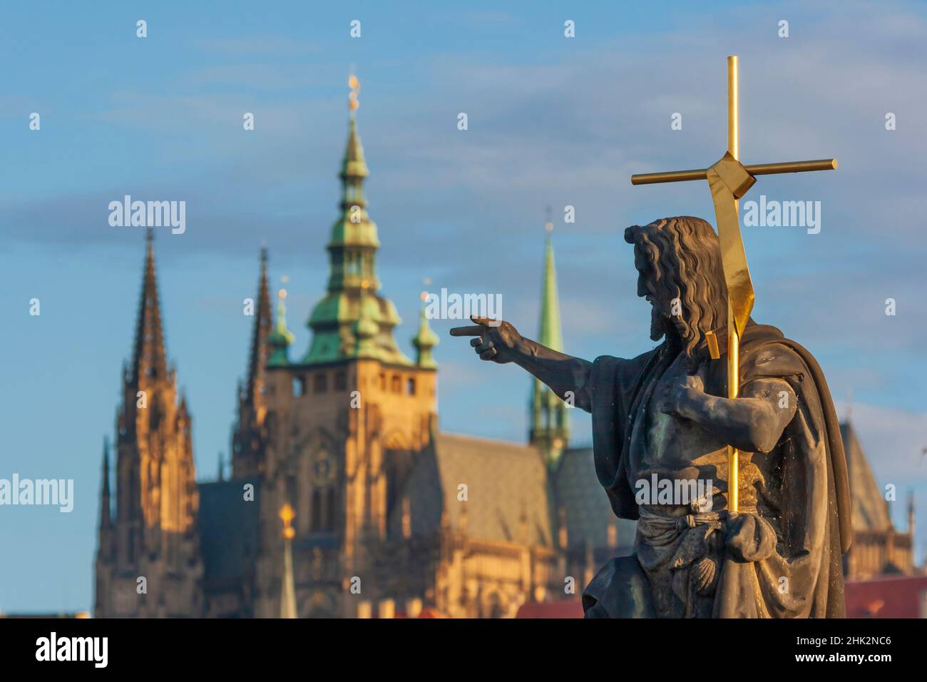 Statue des heiligen Johannes des Täufers auf der Karlsbrücke mit der Prager Burg und der St. Veits Kathedrale im Hintergrund, Prag, Hauptstadt der Tschechischen, UNE Stockfoto