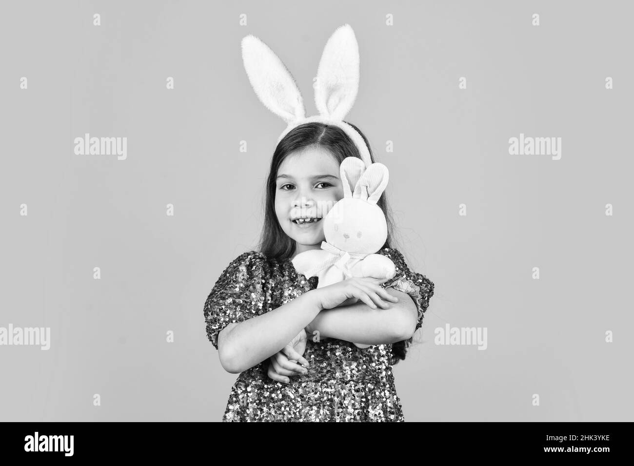 Frühling. Kleines Mädchen halten Hase Spielzeug. Glückliche Kindheit. Niedliches Kind spielen mit Spielzeug. Spielzeug Shop Konzept. Mädchen in lustigen Kaninchenohren. Frohe osterferien Stockfoto