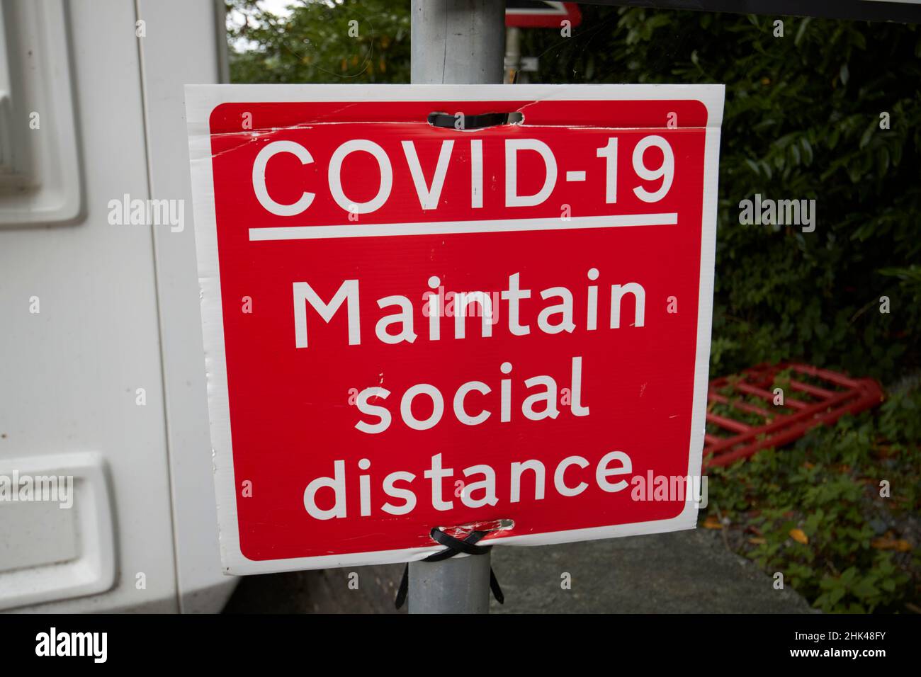 Red covid-19 unterhält soziales Fernschild am fährhafen von windermere in Far sawrey mit Blick auf bowness-on-windermere Lake District, cumbria, Stockfoto