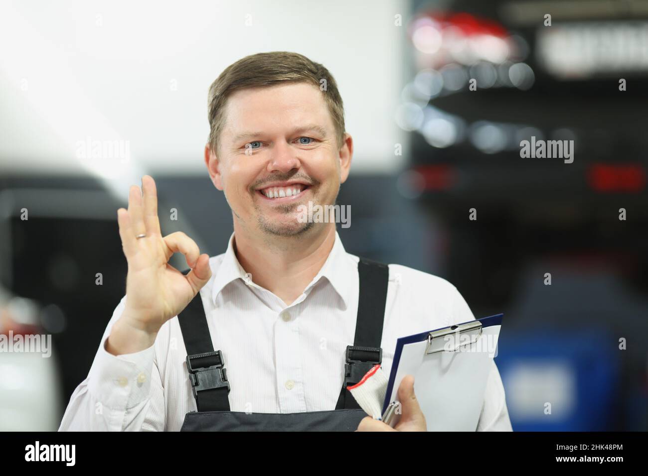 Meister der Werkstatt hält Dokumente und zeigt eine gute Geste in der Werkstatt Stockfoto