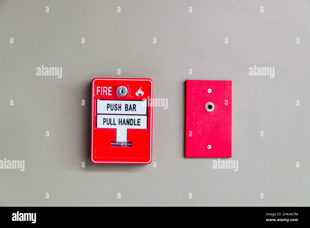 Feueralarm-Presse-Maschine und Feuerwehrmann-Telefonbuchse, die an Betonwand im Gebäude installiert Stockfoto