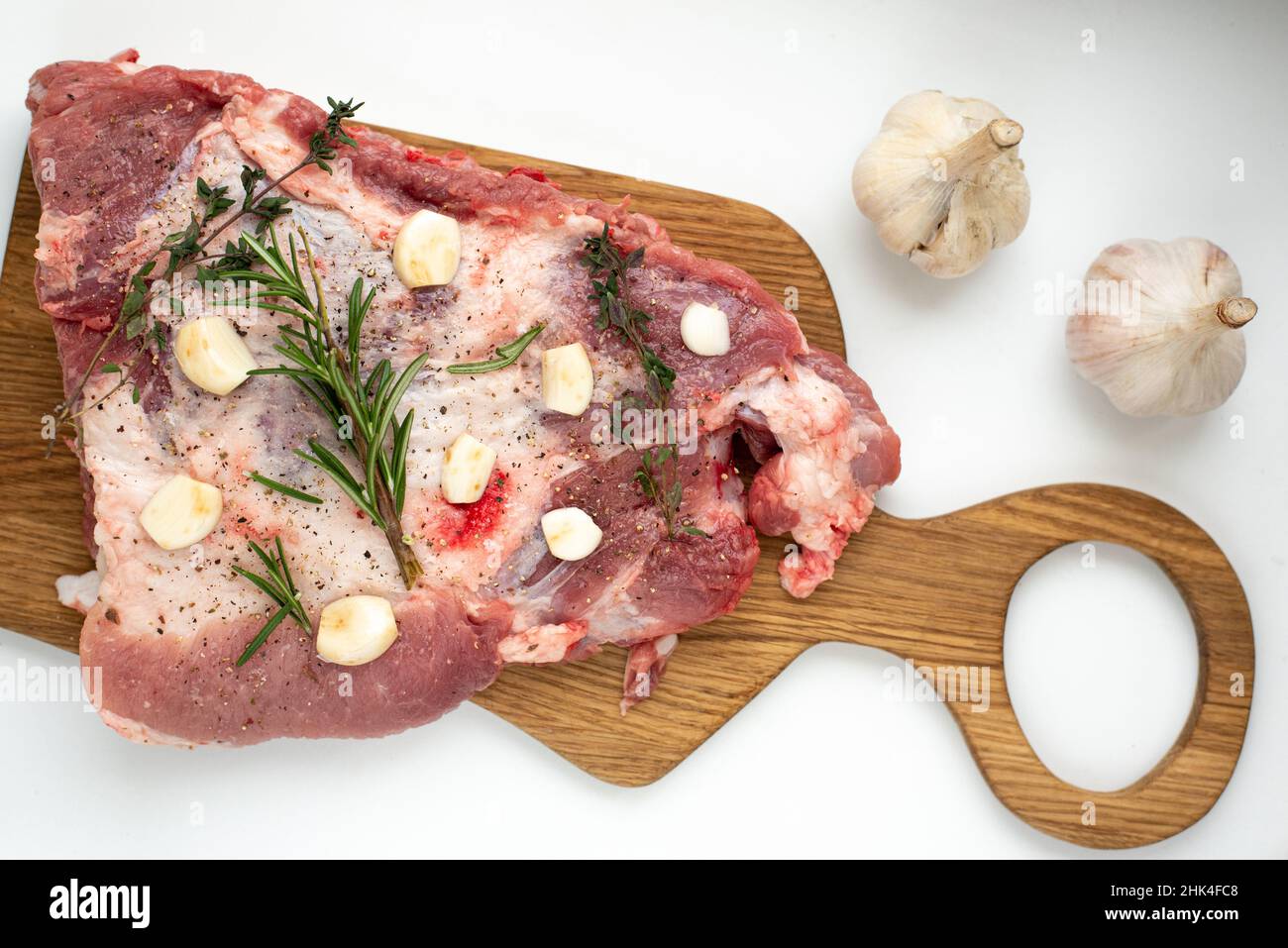 Frische Rippchen mit Rosmarin und Knoblauch auf einem Holzbrett auf weißem Hintergrund Stockfoto