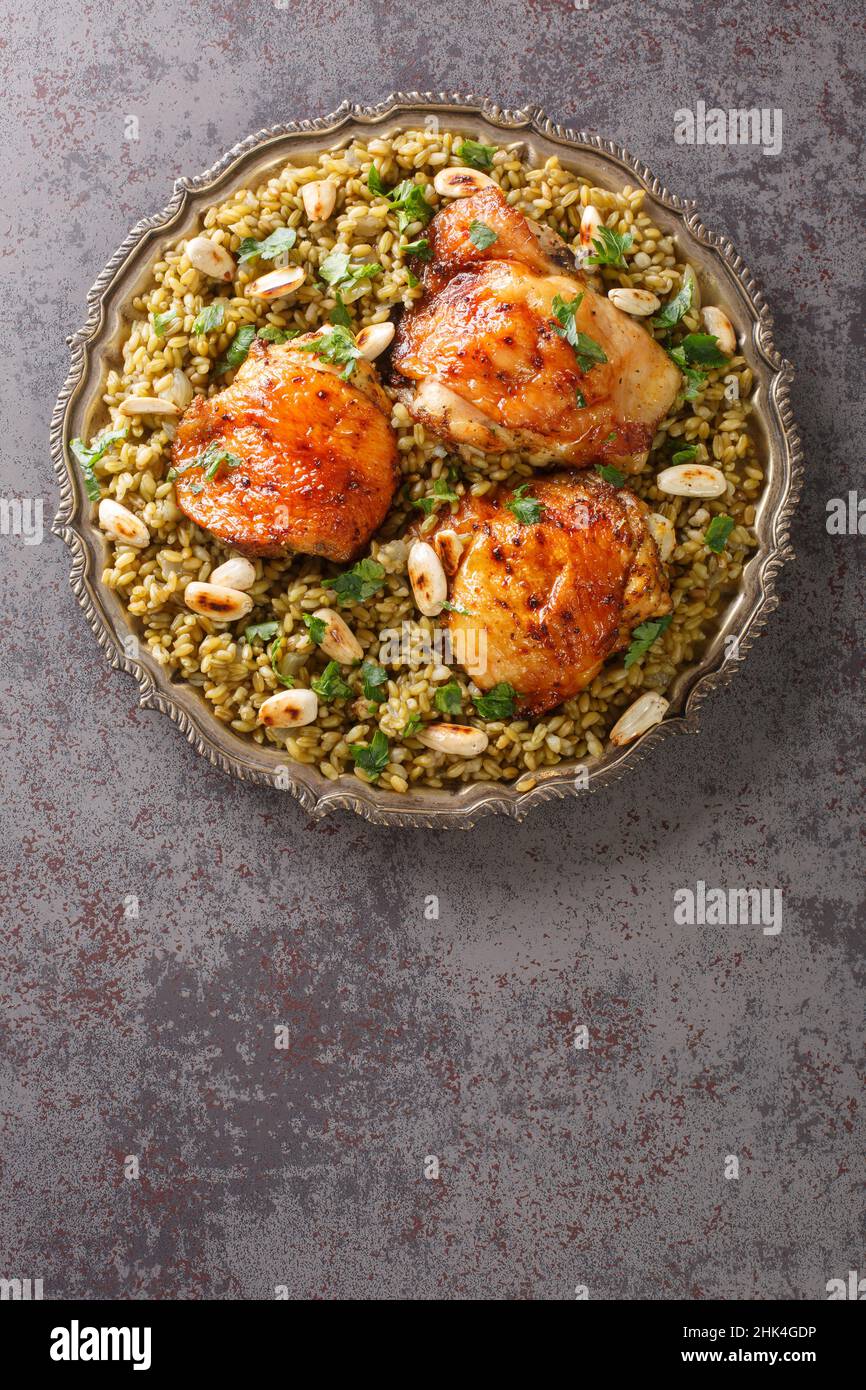 Freekeh mit Huhn, Mandeln beliebtes libanesisches Essen in Nahaufnahme auf einem Teller auf dem Tisch. Vertikale Draufsicht von oben Stockfoto