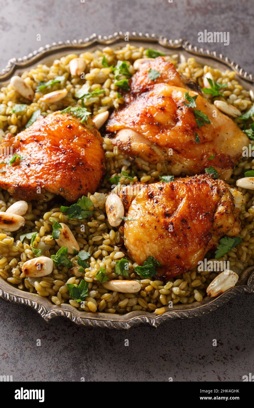 Freekeh mit Huhn, Mandeln beliebte libanesische Küche in Nahaufnahme auf einem Teller auf dem Tisch. Vertikal Stockfoto