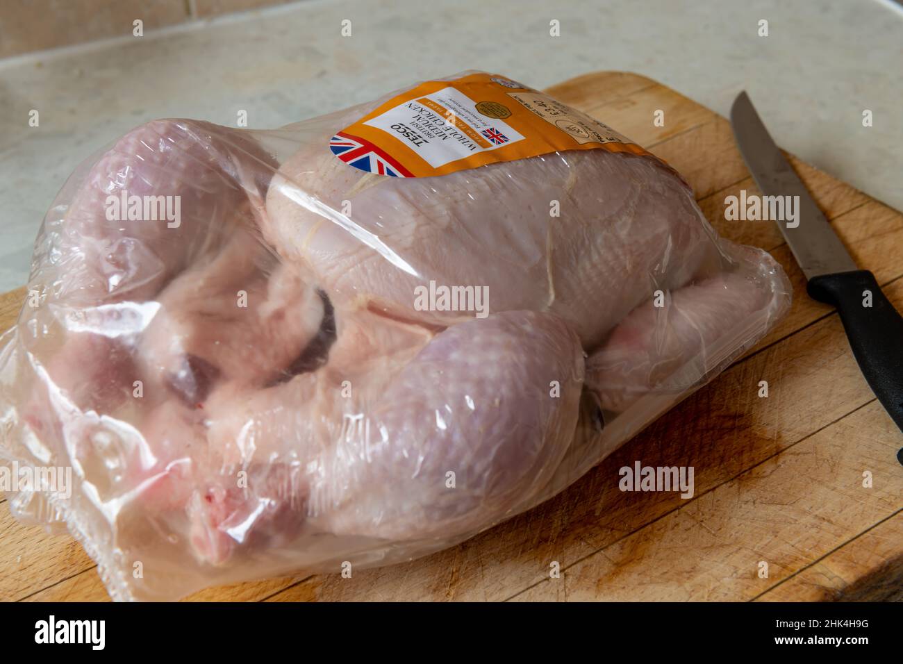 London. GROSSBRITANNIEN: 01.26.2022. Ein verpacktes Huhn aus dem Tesco Supermarkt auf einem Schneidebrett in einer heimischen Küche. Stockfoto