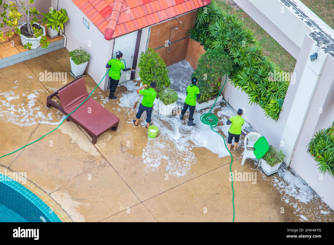 Ein Reinigungsteam bei der Arbeit, das den Pool einer Eigentumswohnung oder eines Hotels und dessen dazugehörige Anlagen aufräumte und aufräumte Stockfoto