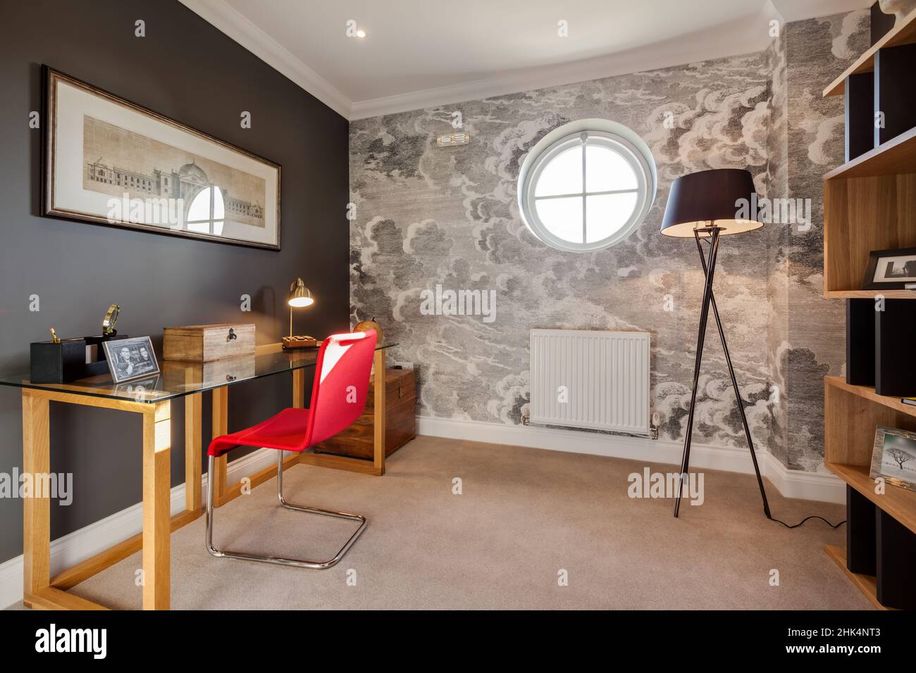 Alconbury Weald, Cambridgeshire - Oktober 17 2016: Arbeitszimmer mit Schreibtisch aus Glas und rotem Stuhl in stilvollem, modernem Zuhause Stockfoto