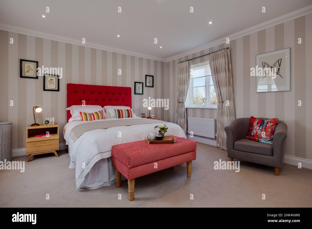Alconbury Weald, Cambridgeshire - Oktober 17 2016: Modernes, stilvolles Schlafzimmer in Aspiration Chic Home mit auffallend rotem Kopfteil und modischem Fell Stockfoto