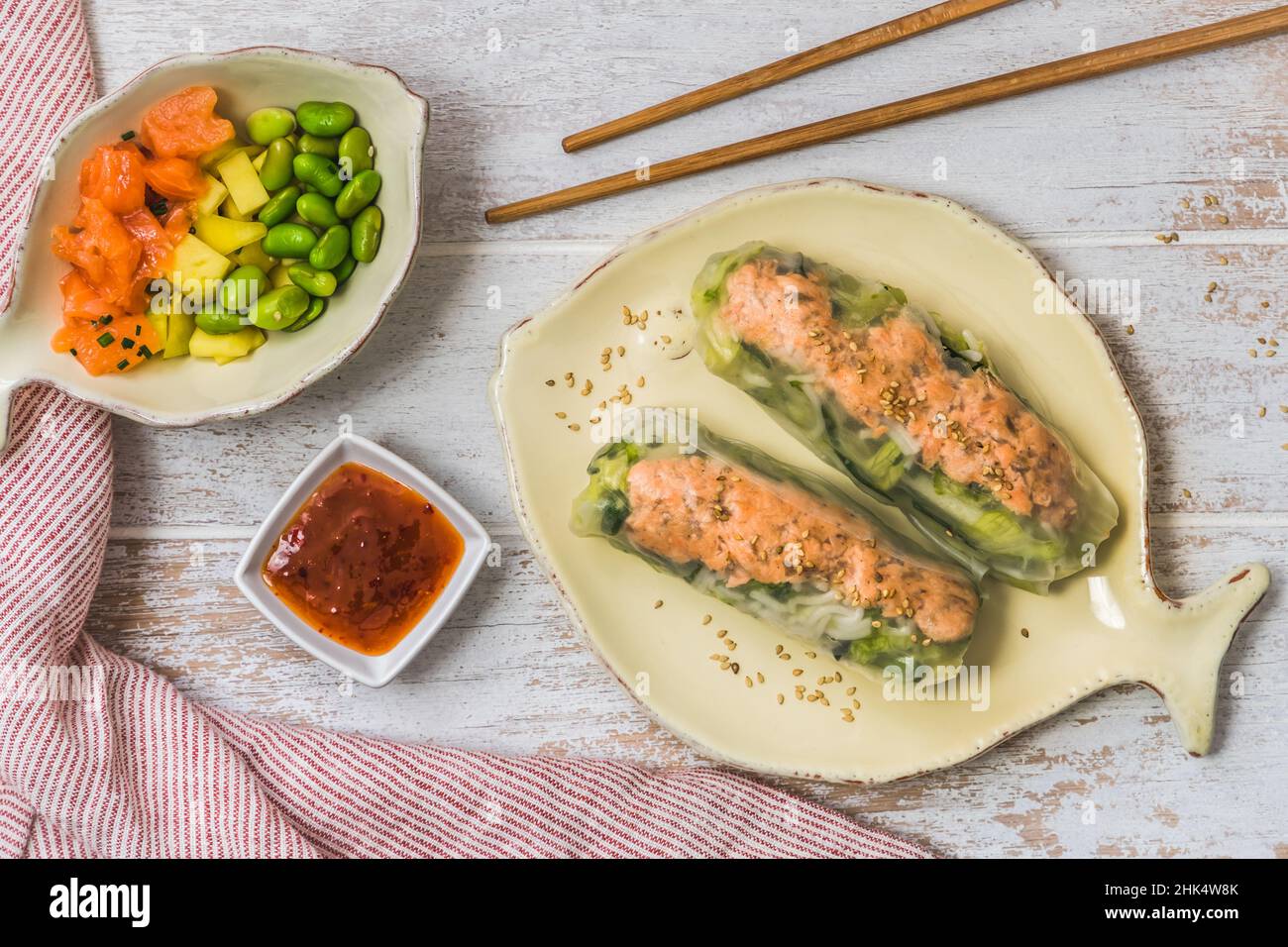 Zwei Sommerbrötchen mit Salat und Lachs und Sauce auf weißem Holzboden, japanisches, asiatisches Essen, Draufsicht Stockfoto