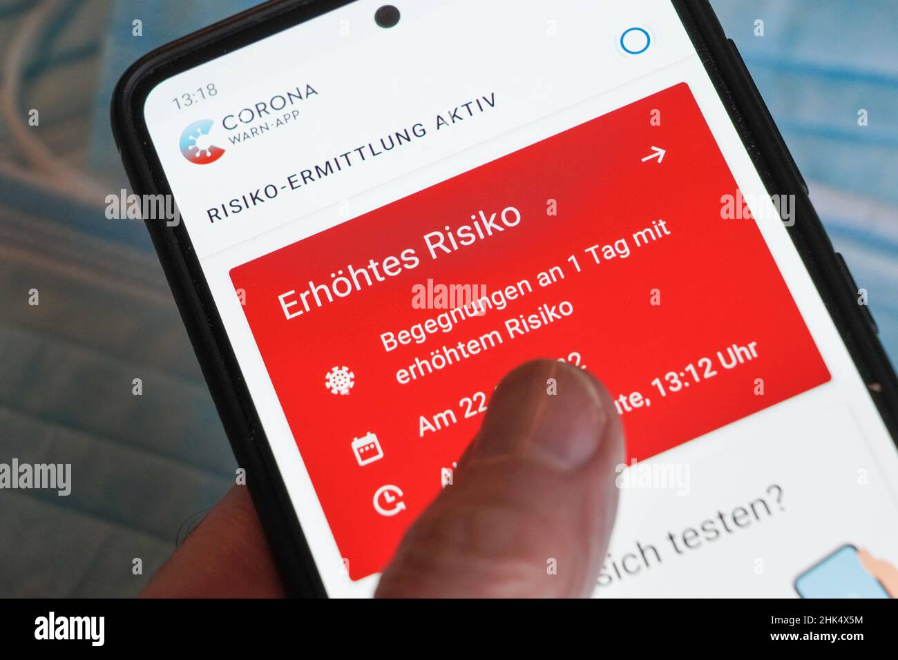 Die deutsche Corona Warning App zeigt ein erhöhtes Risiko auf einem Smartphone, nachdem man eine Person getroffen hat, die positiv getestet wurde. --- die Corona Warn-App zeigt auf einem Smartphone ein erhöhtes Risiko nach einer Begegnung mit einer positiv gestesteten Person an. Stockfoto