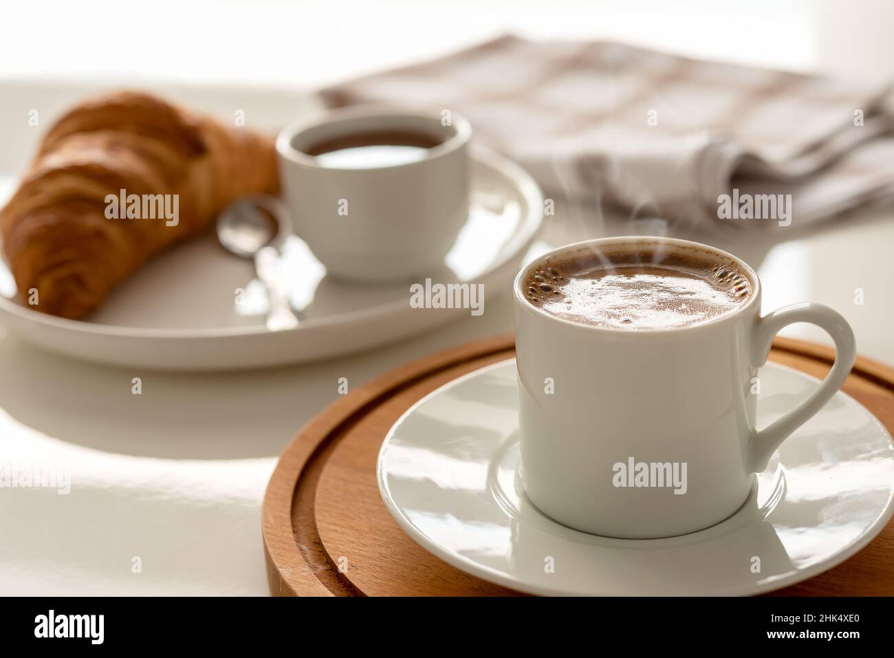 Frühstück mit schwarzem Kaffee und Croissant auf dem Tisch. Stockfoto