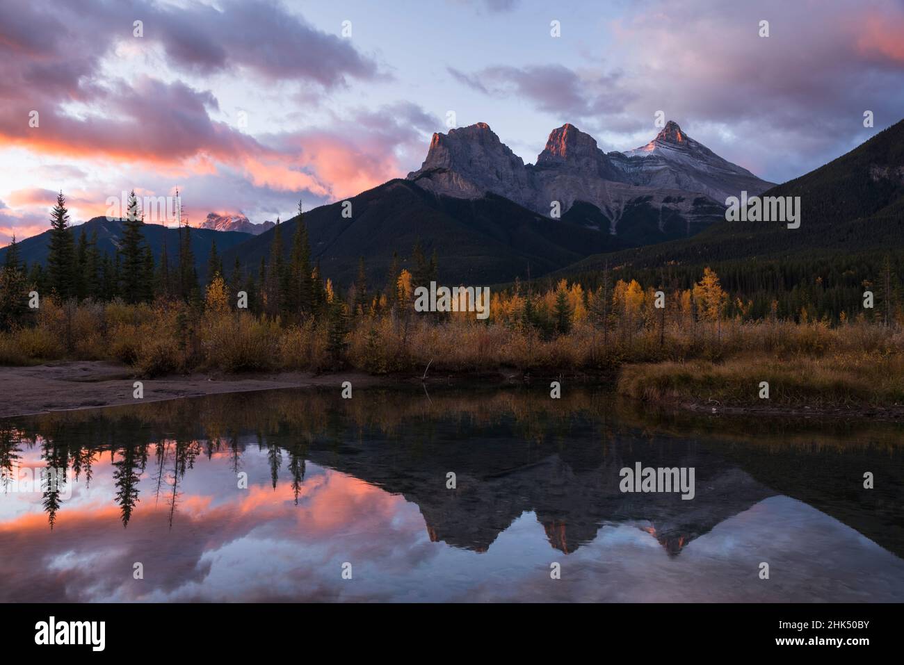 Farbenfroher Sonnenaufgang über Three Sisters am Policeman Creek im Herbst, Canmore, Banff, Alberta, Canadian Rockies, Kanada, Nordamerika Stockfoto