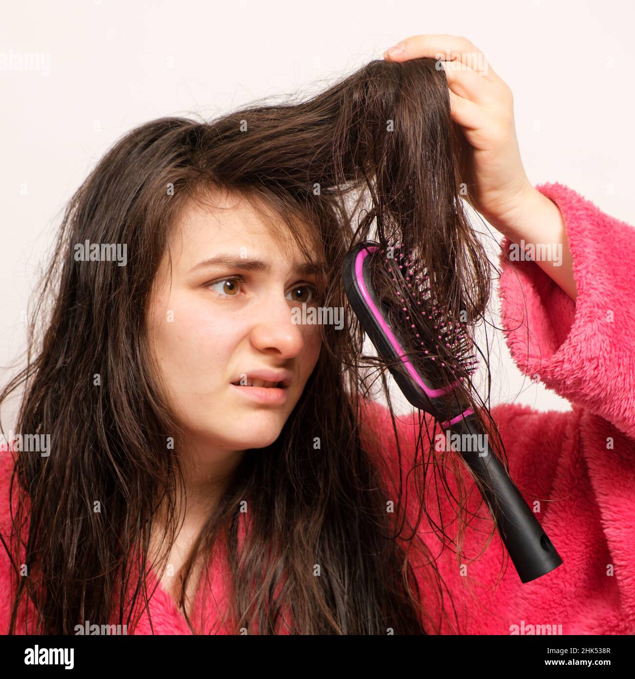 Eine Frau mit nassem, langgewirrtem Haar versucht zu kämmen Stockfoto