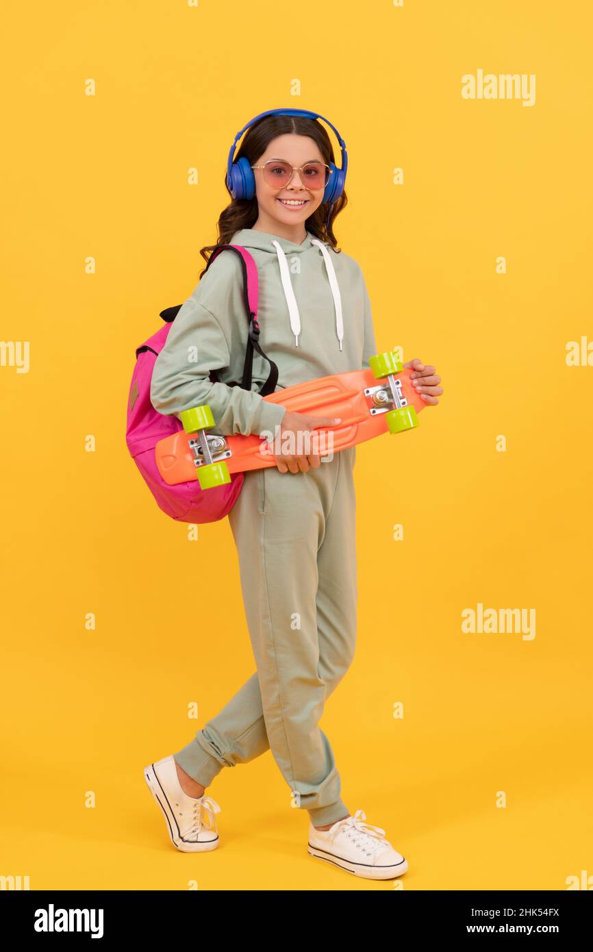 Glückliches Kind in activewear hält Penny Board gelben Hintergrund, Skateboarding Stockfoto