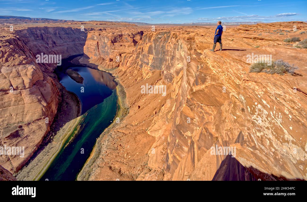 Ein Mann, der am Rand einer Klippe mit Blick auf das Horseshoe Bend in der Nähe von Page, Arizona, USA, Nordamerika, wandert Stockfoto