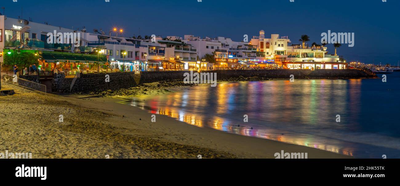 Blick auf Restaurants und Geschäfte mit Blick auf Playa Blanca Beach in der Abenddämmerung, Playa Blanca, Lanzarote, Kanarische Inseln, Spanien, Atlantik, Europa Stockfoto