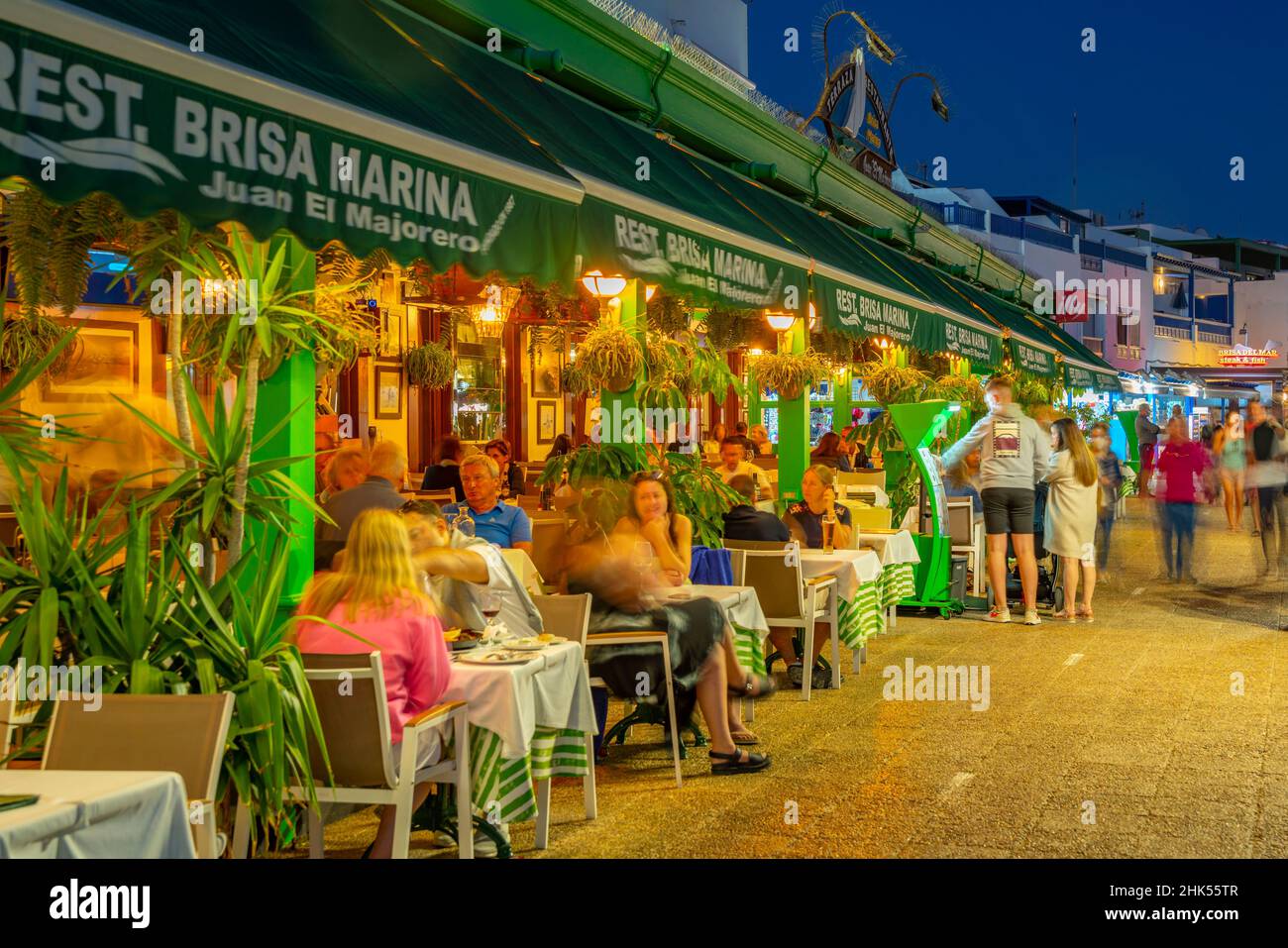 Blick auf Restaurants und Geschäfte mit Blick auf Playa Blanca Beach in der Abenddämmerung, Playa Blanca, Lanzarote, Kanarische Inseln, Spanien, Atlantik, Europa Stockfoto