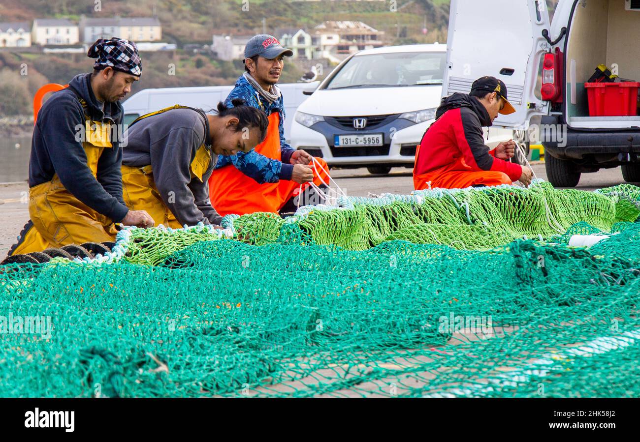 Die irische Fischereimannschaft besteht aus ausländischen Staatsmitgliedern, die Netze ausbessern Stockfoto