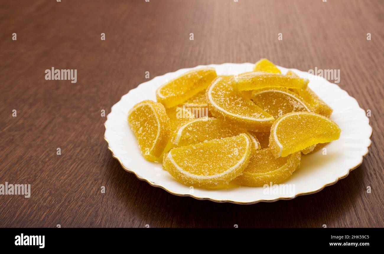 Marmorieren Sie Zitronenscheiben auf einem weißen Teller auf einem Holztisch in Nahaufnahme Stockfoto